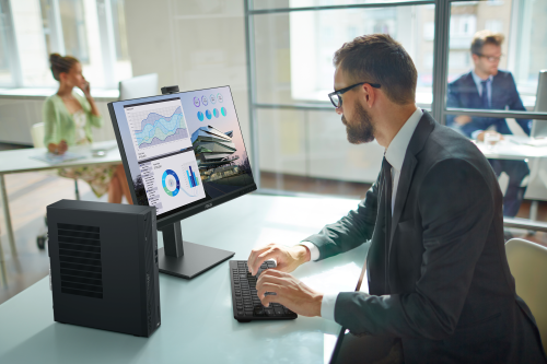 A businessman sitting at a desk with an ASUS desktop in an office setting.